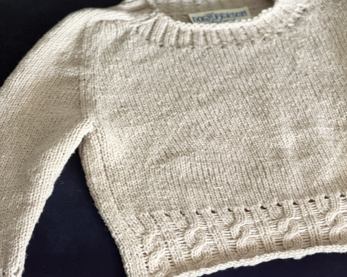 Close-up of a beige knitted sweater with cable patterns at trims