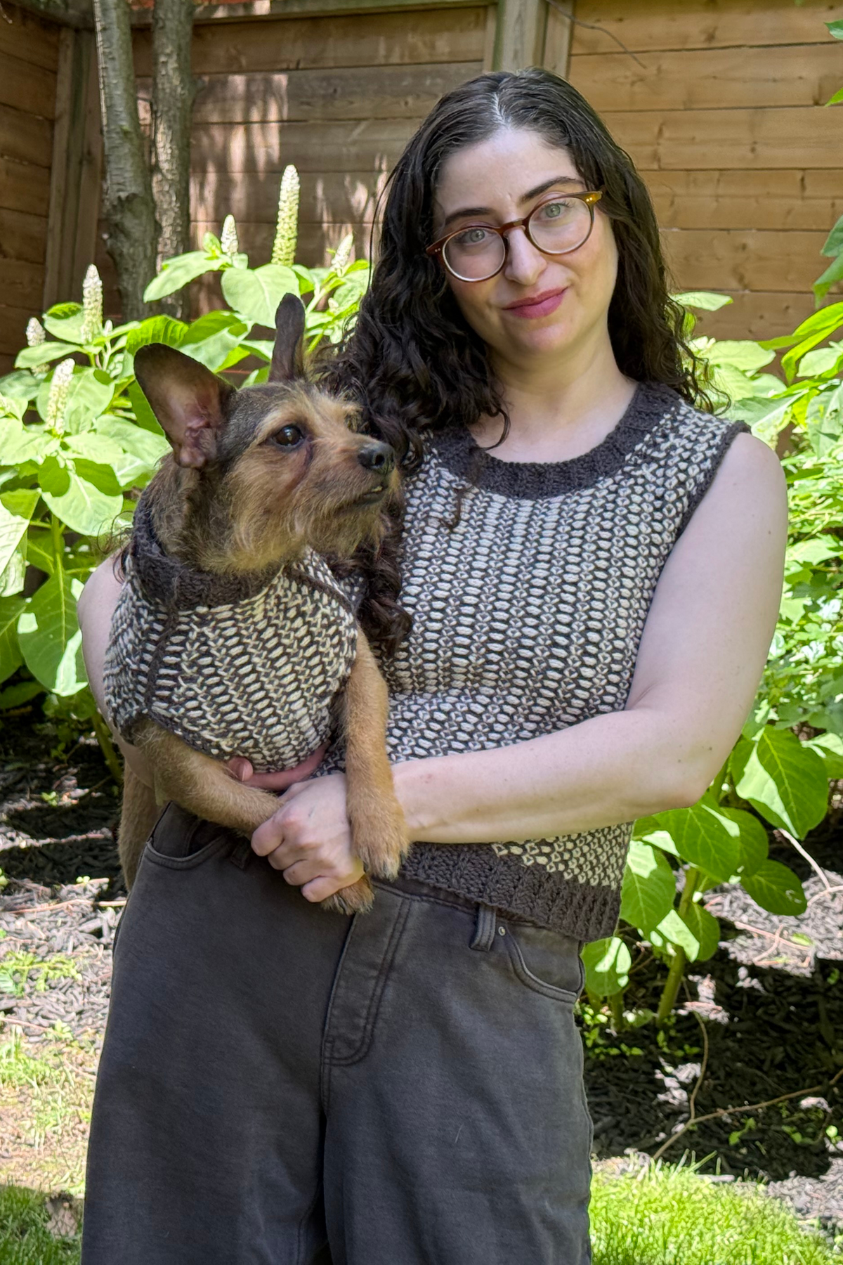 Woman and small brown dog in matching grey and cream pattern sweaters.